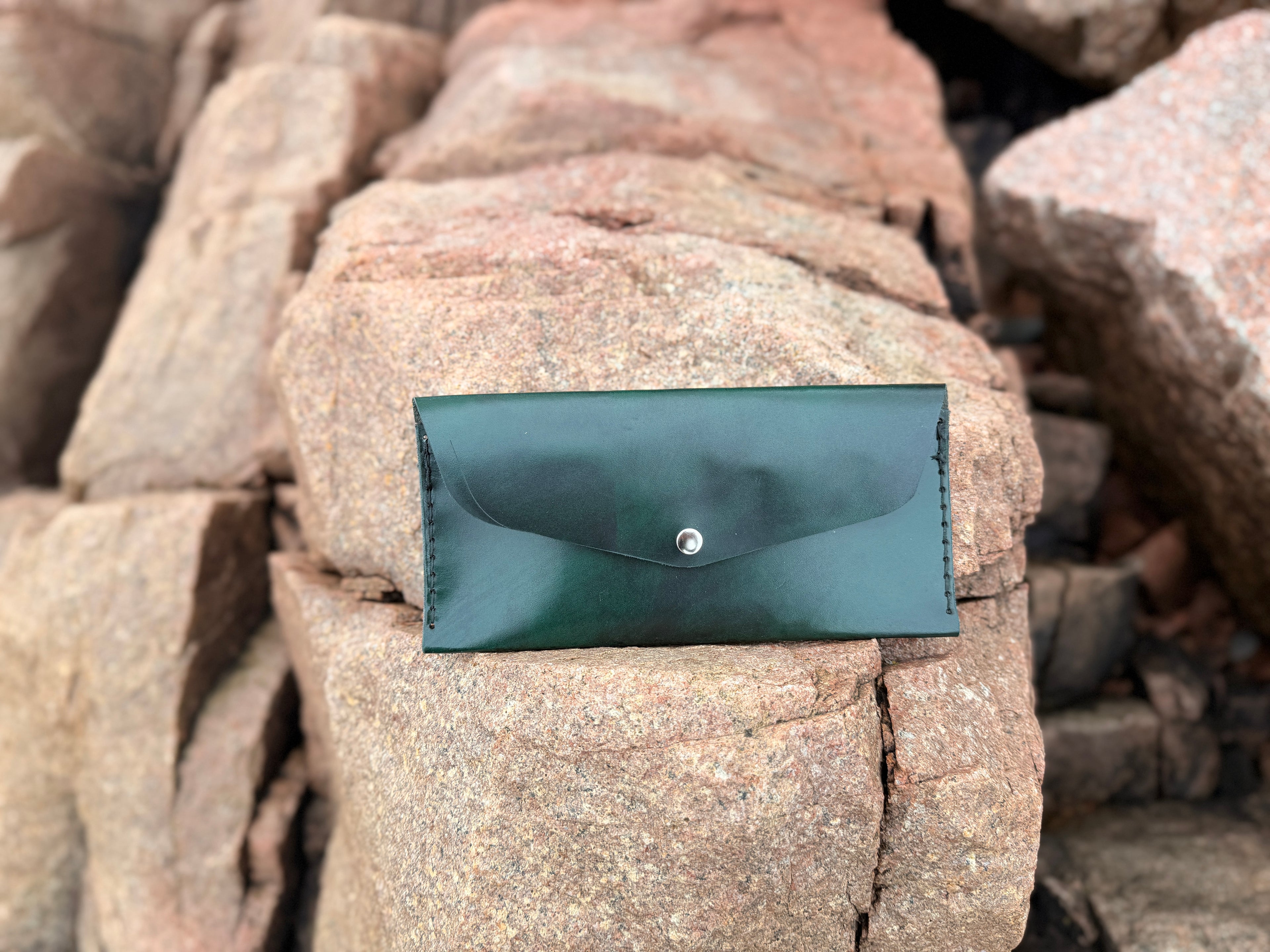 Forest green leather envelope wallet open on granite